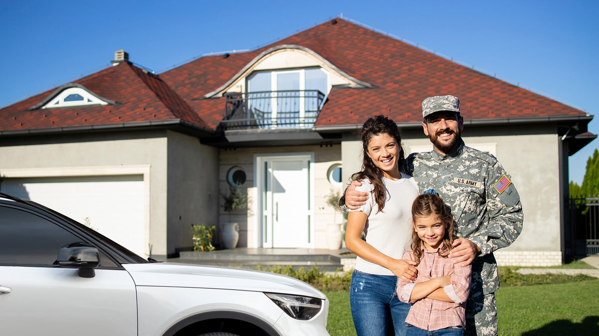 Member of the U.S. Army with family in front of home with car