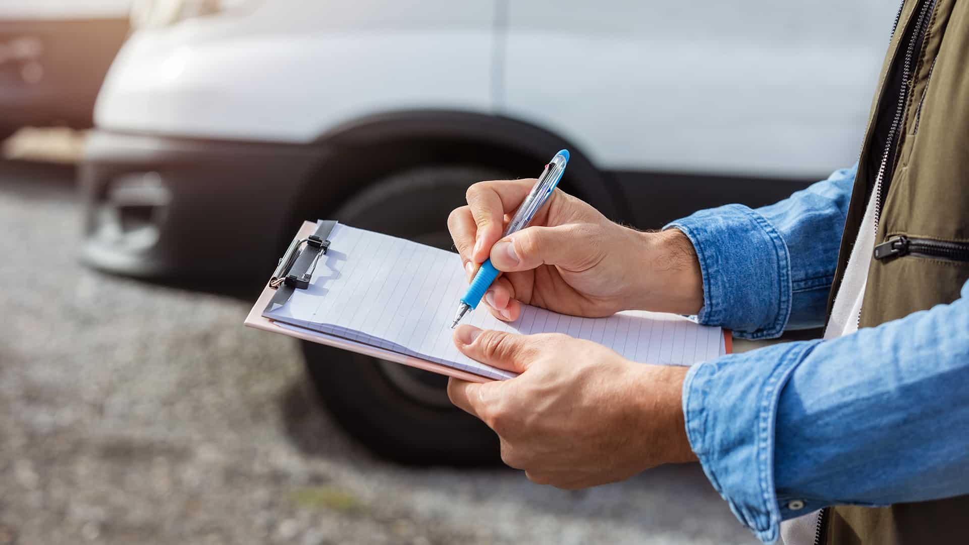 Person holding a clipboard of paper and a pen, standing by a car.